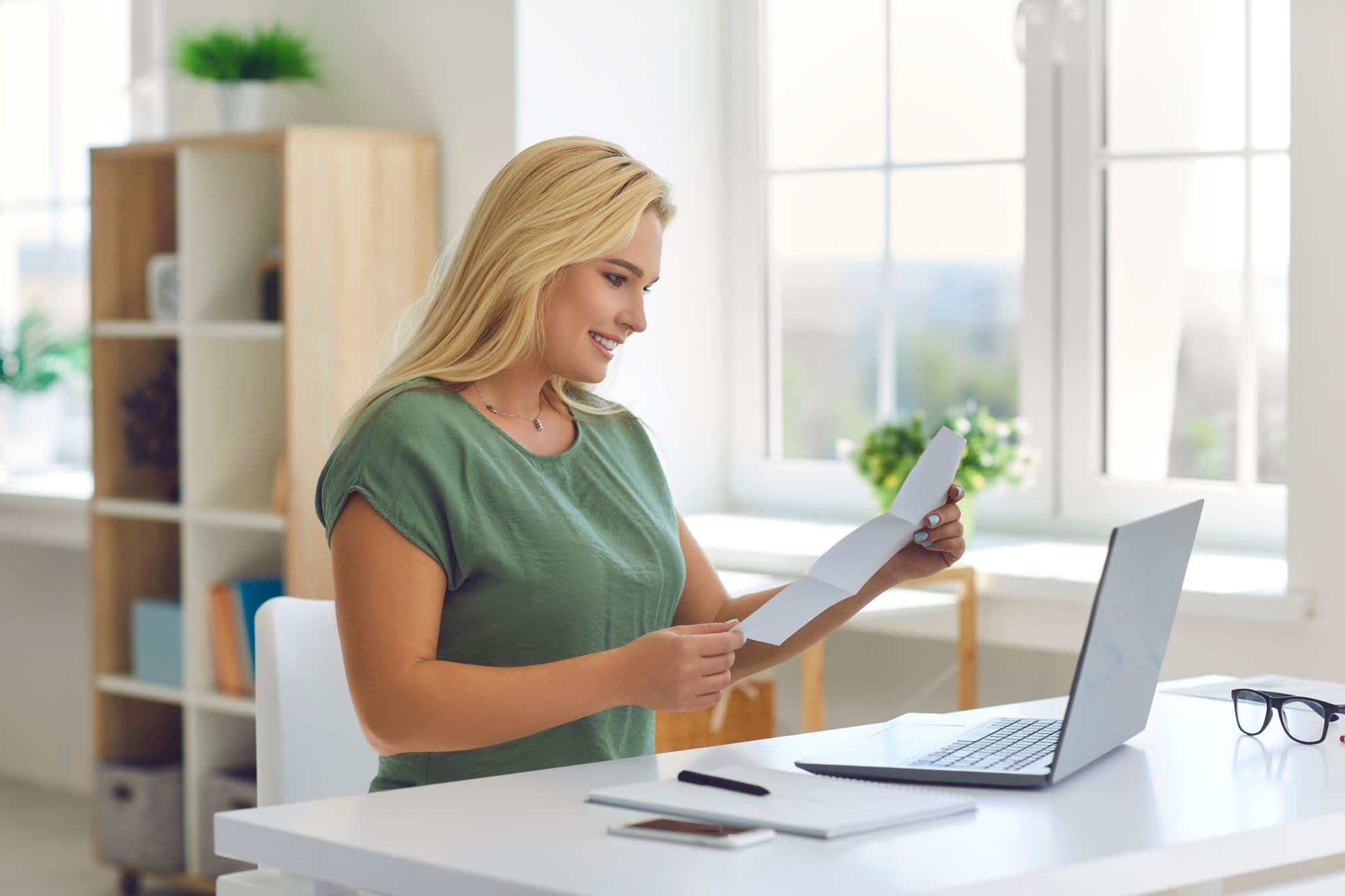 blonde-woman-holding-piece-of-paper-and-smiling