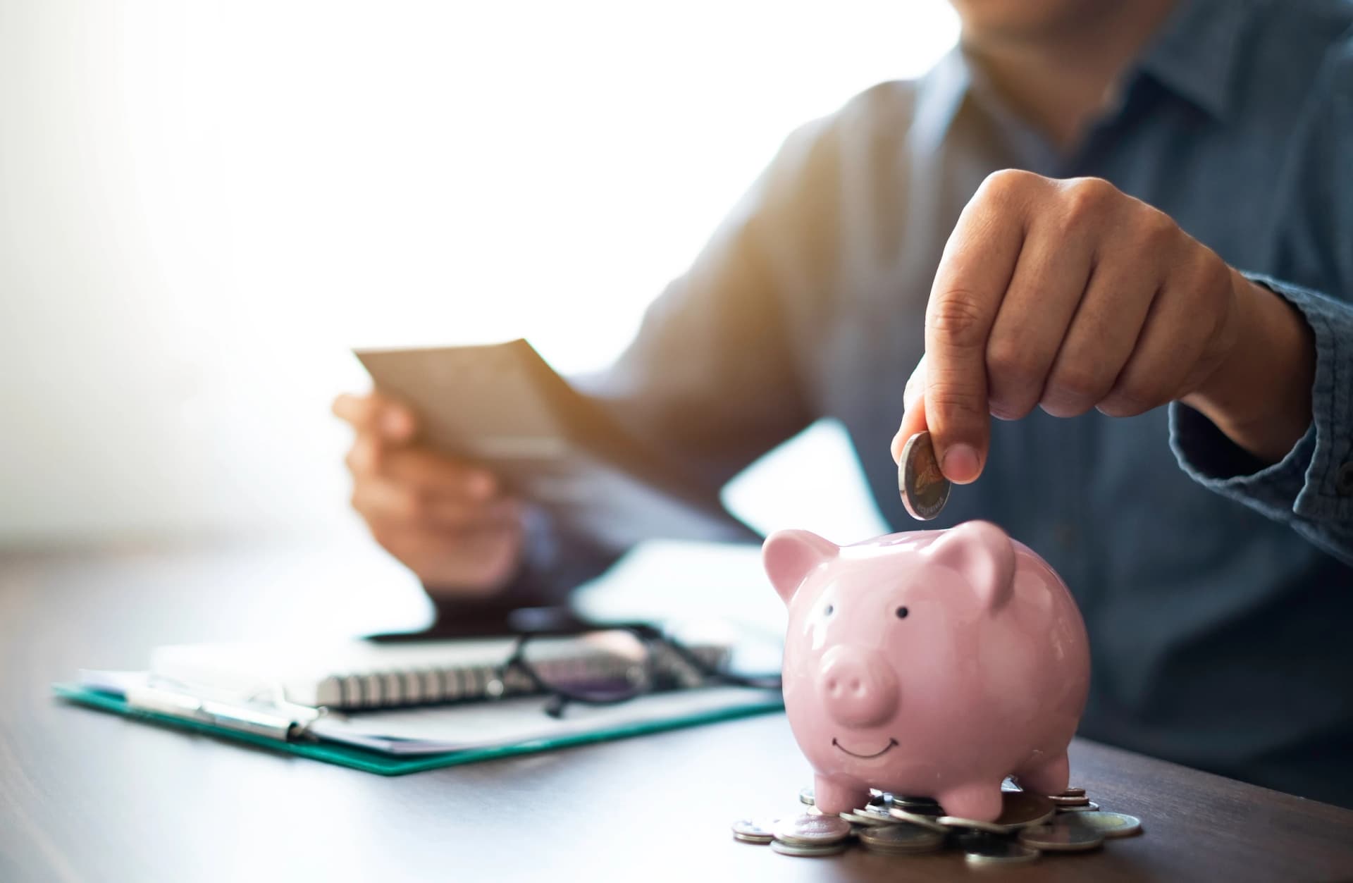 man hand putting coins in pink piggy bank to save money man hand putting coins in pink piggy bank to save money