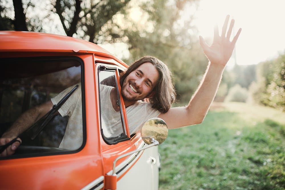 a-young-man-driver-in-a-car-on-a-roadtrip-through-JUBEX8M