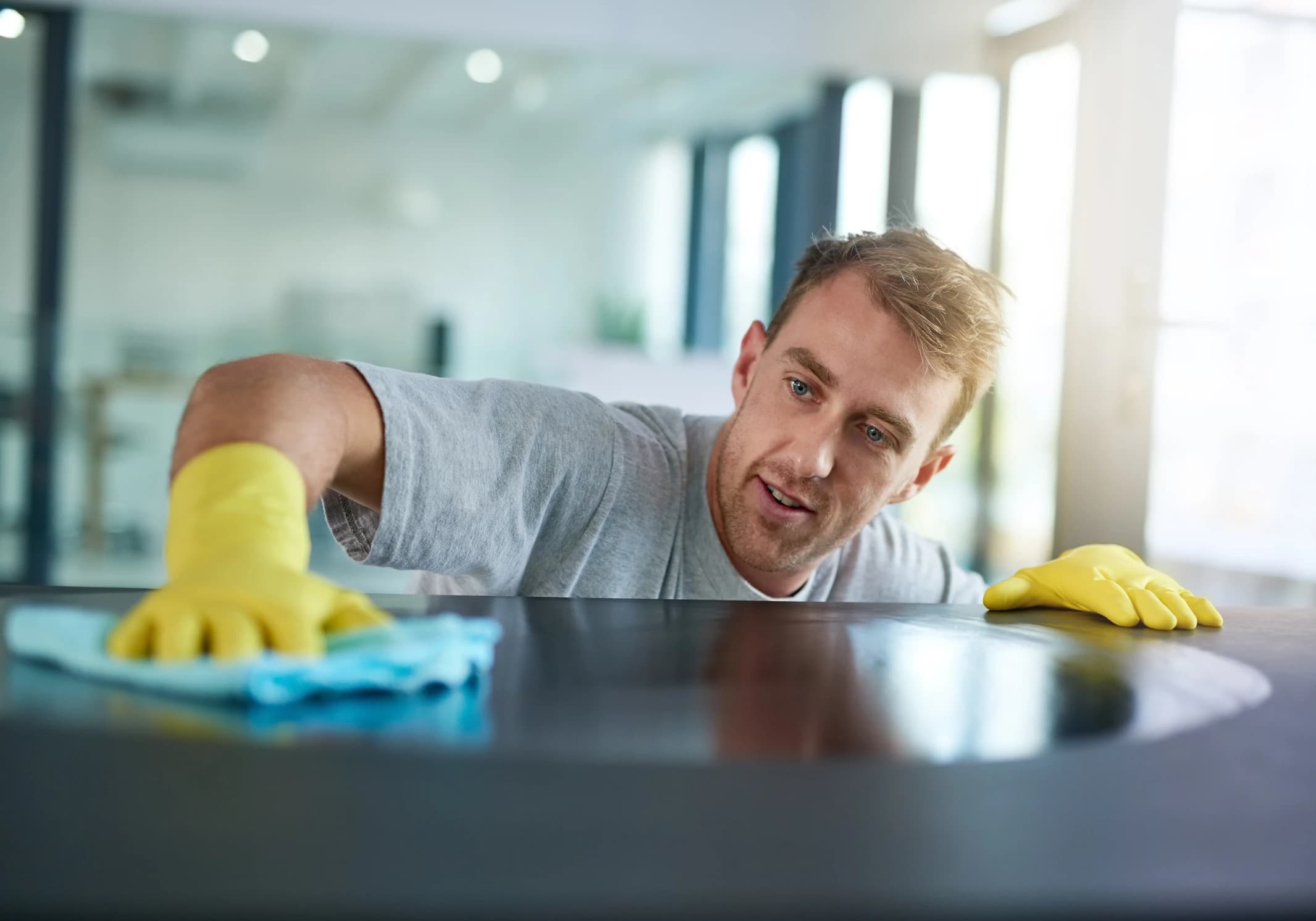 Man with gloves cleaning surface in office